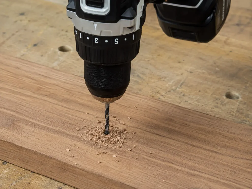 A cordless drill being used to make a pilot hole in a piece of hardwood timber on a workbench