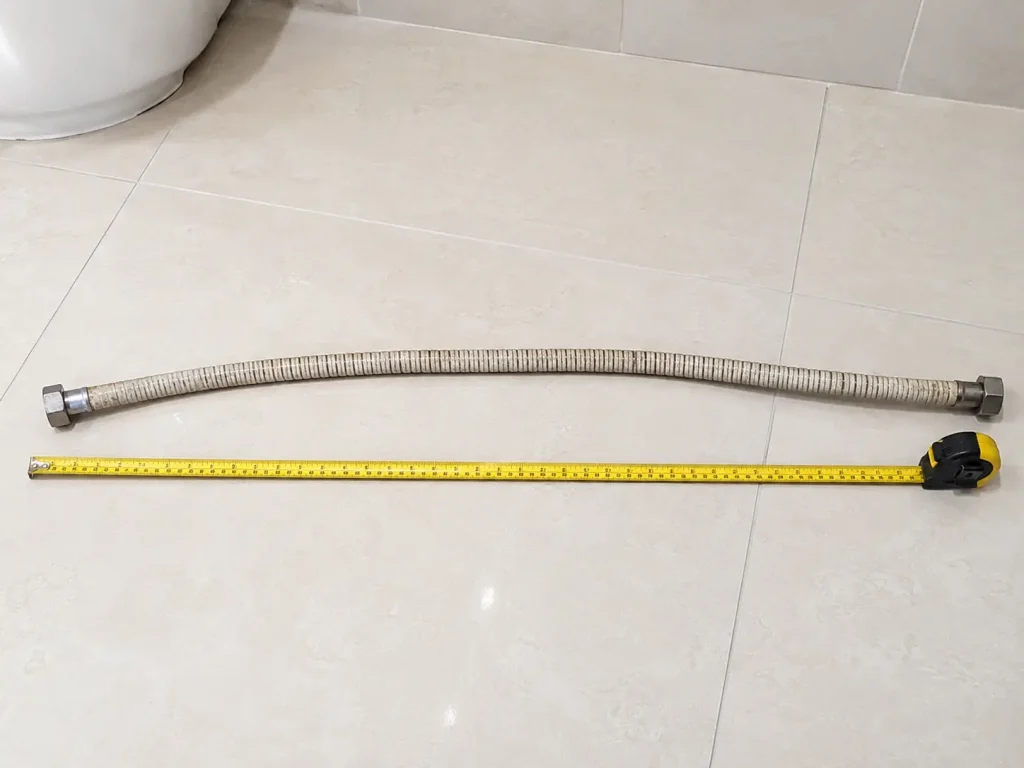 Measuring the length of an old bidet hose before buying a replacement.